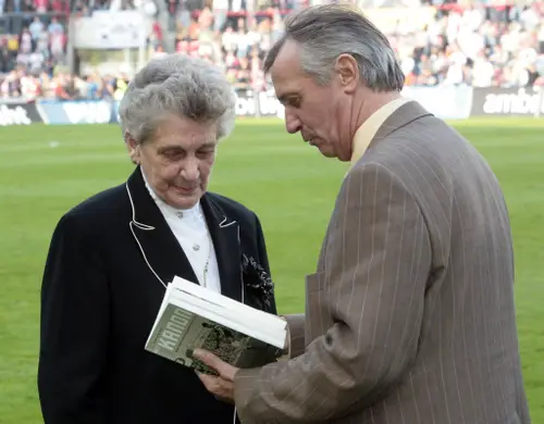 Willy van der Kuijlen biedt mevr. Dillen, weduwe van Coen Dillen, het eerste boek over haar man aan