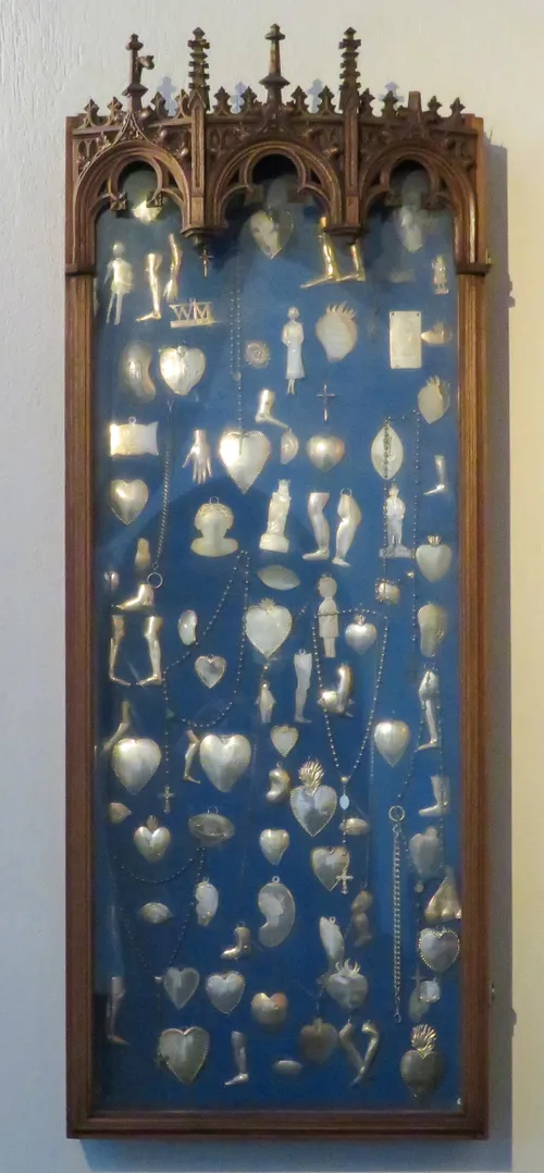 De vitrine met de ex-voto’s hangt bij het Mariakapel, links vooraan in de kerk