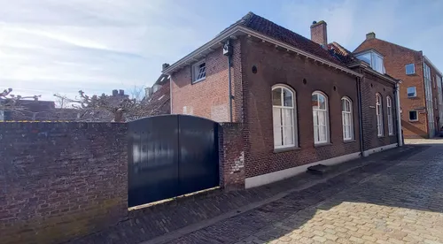 Het huidige zijaanzicht van het monument met v.l.n.r.: muur, poort, atelier en voormalig hoofdgebouw van de marechausseekazerne