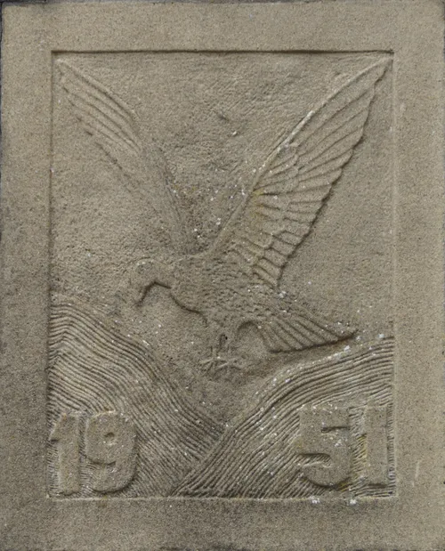 De voorzijde van de pomp is versierd met een plaquette, voorstellende een GIER, zwevende boven de BERGEN (duinen) met het jaartal 1951. Met gieren wordt hier bedoeld het heen en weer bewegen van de stuifzandheuvels.