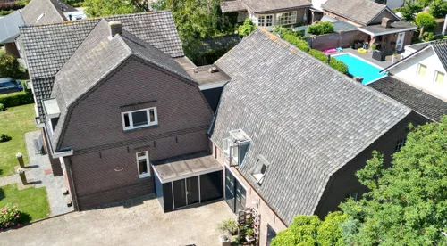 Droneopname van de mansardedaken van de hoofdvleugel (linksboven), zijvleugel (midden) en bedrijfsdeel (rechts).