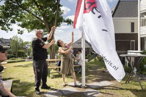 Een bewoner en Zideris directeur ai hijsen de vlag