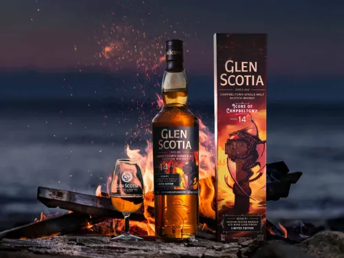 A bottle of Glen Scotia Icons of Campbeltown Dragon 14 Year Old single malt whisky in front of a campfire