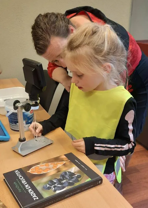 Een kind determineert zaden met een microscoop