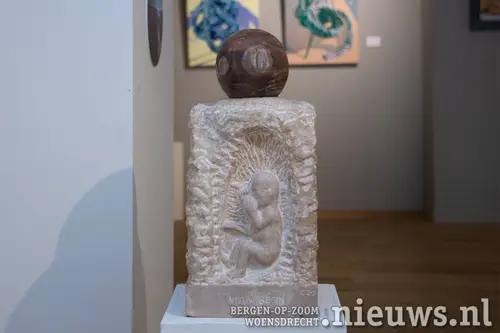 Het beeld 'Circle of Life' in kalkzandsteen. Op de vier vlakken zijn de verschillende stadia van het leven afgebeeld.