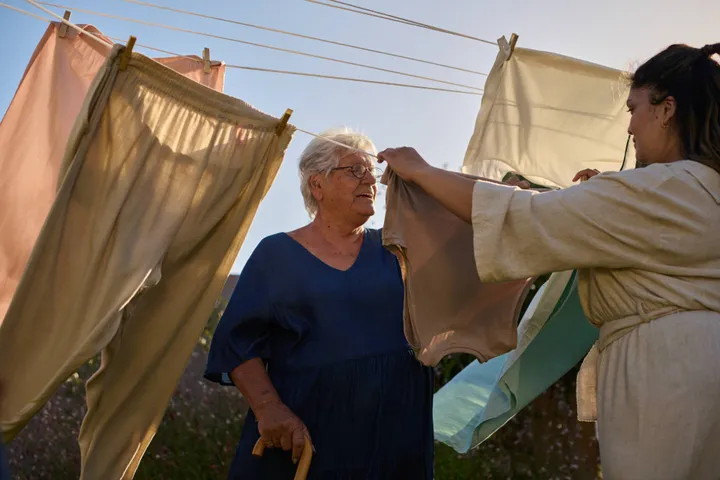 TENA CGR Sustainability Lifestyle Garden Elderly Person Being Helped Hanging Washing Landscape