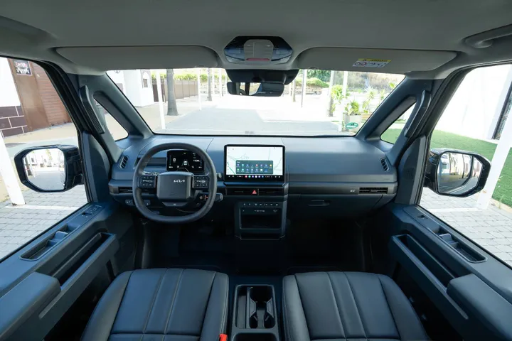 Gli interni della Kia PV5 con sedili neri, display dell'infotainment da 12,8 pollici e quadro strumenti digitale