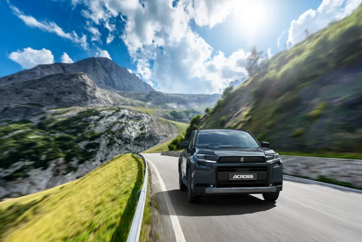 Nuova Suzuki Across plug-in hybrid in ripresa dinamica anteriore su una strada con montagne dietro