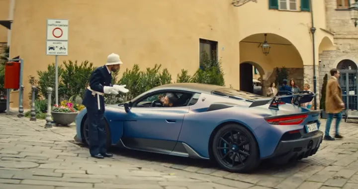 Maserati GT2 Stradale blu metallizzato ferma nel centro storico di Sanremo mentre il guidatore parla con un vigile urbano, scena tratta dallo spot TV della Fiat Topolino