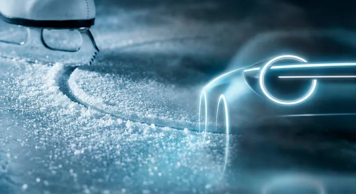 Dettaglio di un pattino che taglia il ghiaccio con sullo sfondo la scia luminosa al neon di un'auto concept Lancia, in tonalità blu elettrico.