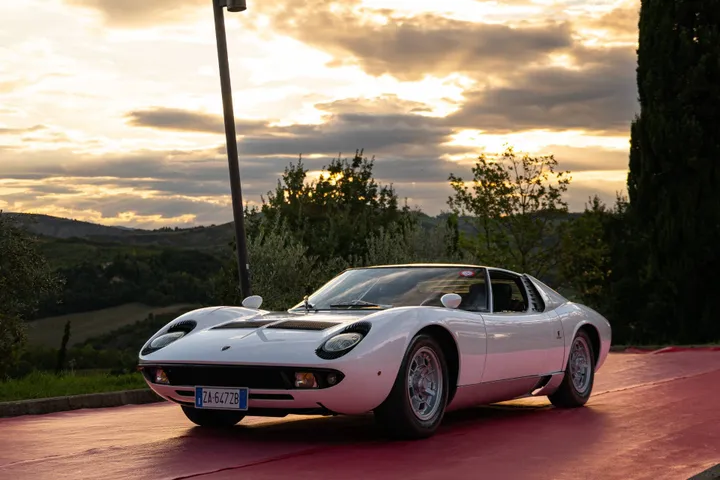 Esemplare di Lamborghini Miura P400 di colore bianco ferma su strada con tramonto sullo sfondo