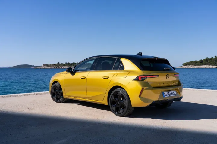 Opel Astra di colore giallo statica con il mare dietro ripresa posteriormente