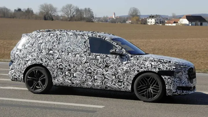 Nell'immagine spia si vede il nuovo Q9 di Audi visto di lato su una strada pubblica