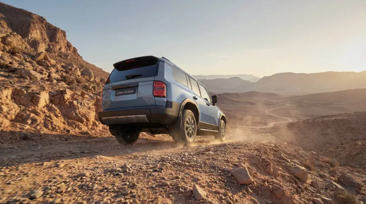 Toyota Land Cruiser di lato di colore blu posteriore che procede su una strada sterrata
