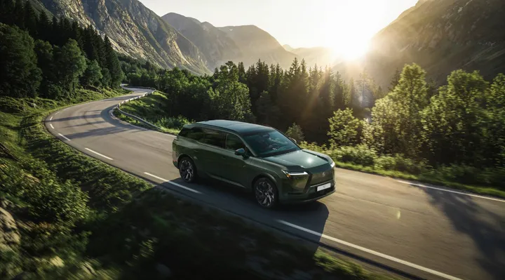 Lexus TZ di colore verde ripresa dall'alto laterale che percorre una strada di montagna al tramonto