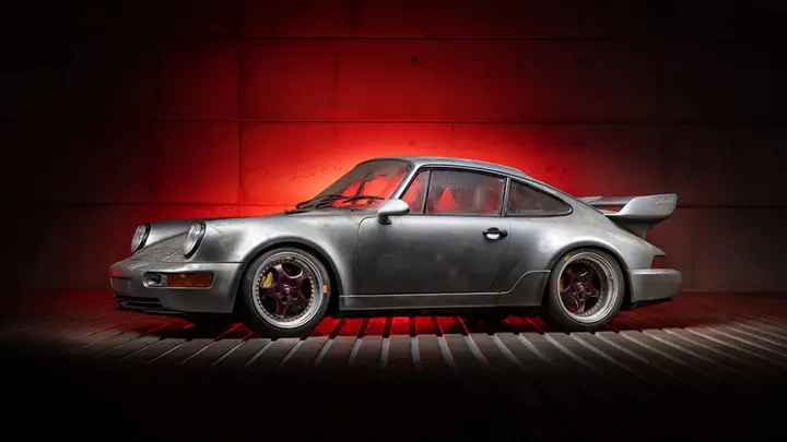 Nell'immagine si vede una Porsche Carrera RSR Strassenversion su uno sfondo rosso