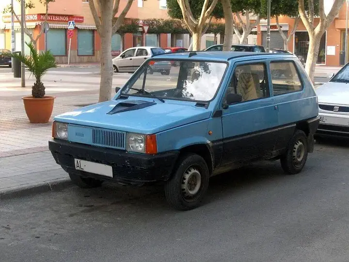 Nell'immagine si vede una Seat Panda azzurra parcheggiata in strada