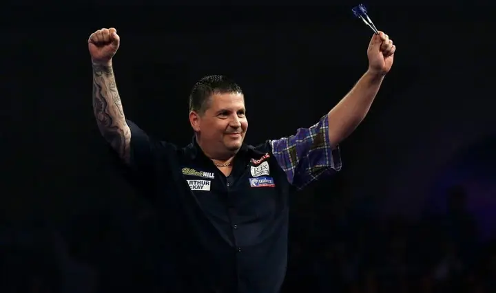 Gary Anderson raises his arms in the air.