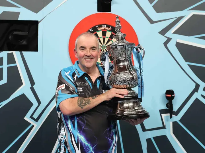 Phil Taylor hält die Trophäe.