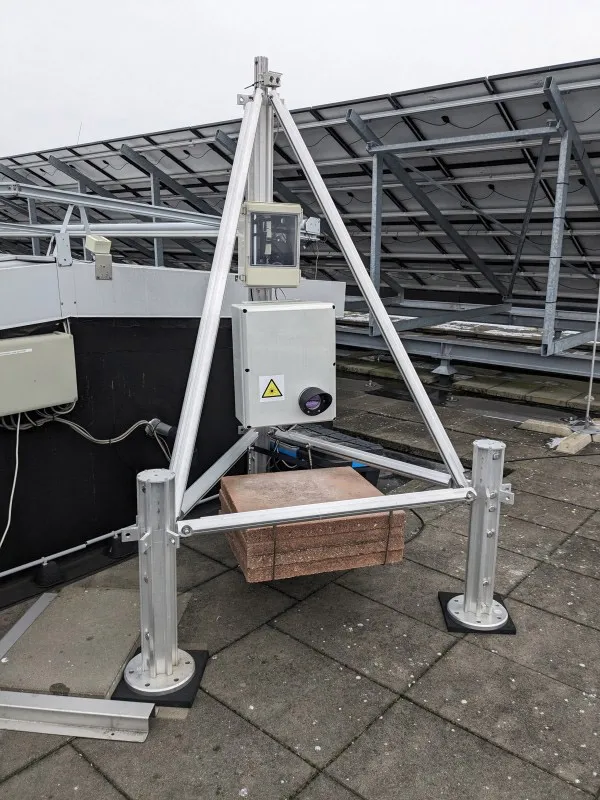 Close-up van de optische antenne op het dak van Flux, gemonteerd op zijn steunframe. De eigenlijke antenne is de grijze doos. Daaruit steekt de apertuur waardoor het infrarode licht wordt verzonden en ontvangen.