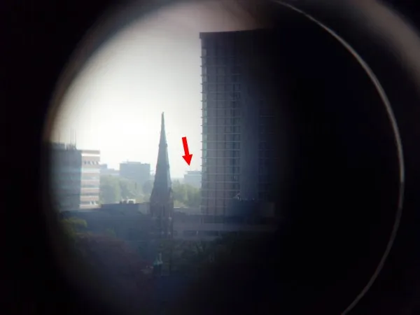 Zicht vanaf Flux door een verrekijker. De rode pijl geeft de positie aan van de andere optische antenne op het dak van gebouw 37 van de High Tech Campus.