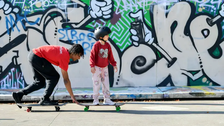 Scholarshipper begeleidt meisje bij haar eerste skateboardritje ©Krajicek Foundation _ Maaike Petri