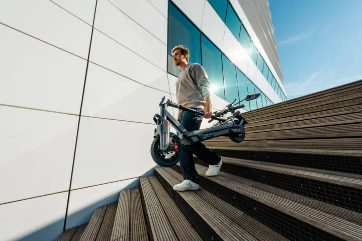 MAX G3 NL - Men carrying eKickScooter in stairs