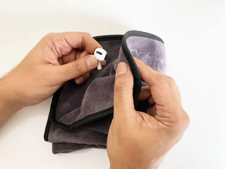 using a microfiber cloth to clean earbuds