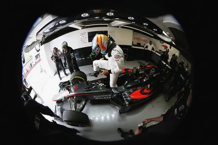 Fernando Alonso climbs from his car in the garage.