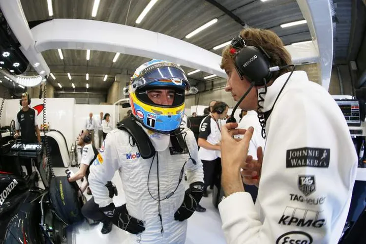 Fernando Alonso talks to an engineer in the garage.