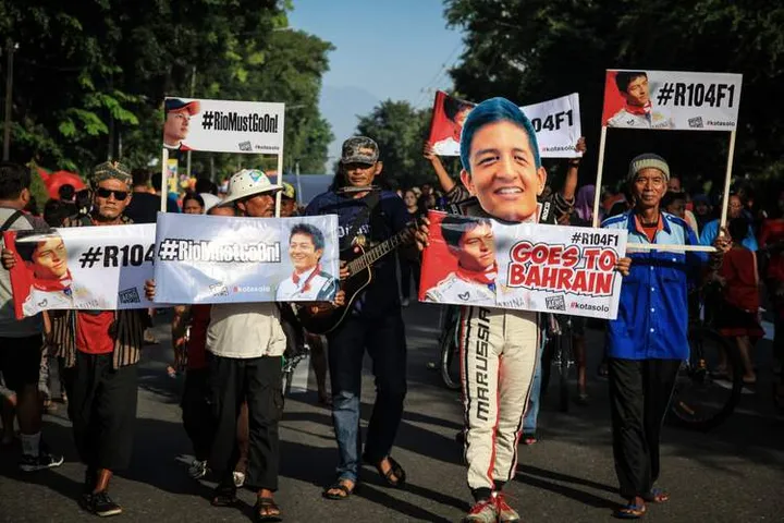 Warga Solo mengusung poster dukungan untuk Rio Haryanto saat pelaksanaan Hari Bebas Kendaraan Bermotor atau Car Free Day Solo, Jawa Tengah, Minggu (3/4).
