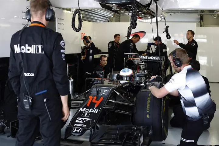 Team members prepare the car of Fernando Alonso in the garage.