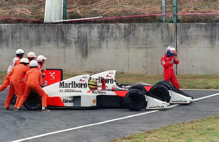 Ayrton Senna of Brazil is given a push from circuit marshals for a restart while his teammate and bitter rival Alain Prost of France leaves his car to abandon the race after the two collided in a chicane during the Japan Formula One Grand Prix in Suzuka 22 October 1989. Senna received the chequered flag but was later disqualified after being accused of receiving an illegal push from marshals and of taking a short cut through the chicane. AFP PHOTO TOSHIFUMI KITAMURA (Photo credit should read TOSHIFUMI KITAMURA/AFP/Getty Images)