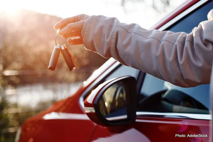 Young woman holding car keys in hand. Happiness of buying the fi
