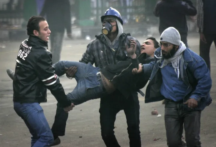 protesters carry an injured fellow protester