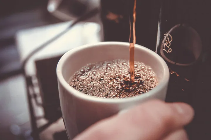 Kopje koffie dat gevuld wordt aan koffiemachine