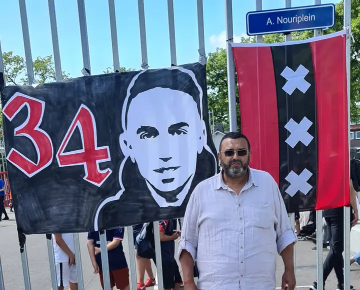 <b><i>Vader Mohammed Nouri poseert trots bij de spandoeken onder het gloednieuwe naambordje, dat nu de naam van zijn zoon draagt.&nbsp;</i></b>