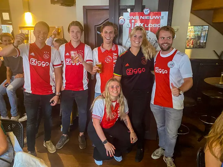 Cynthia (in het derde tenue) met een aantal cafégasten tijdens een avondje Champions League