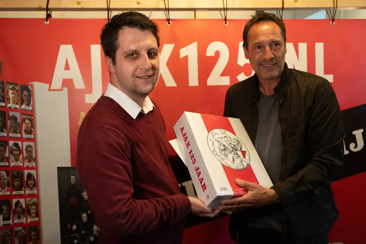 John van 't Schip krijgt het boek 'Ajax 125 jaar' uit handen van AS-hoofdredacteur Bart Veenstra, die onderdeel uitmaakte van het schrijverscollectief.