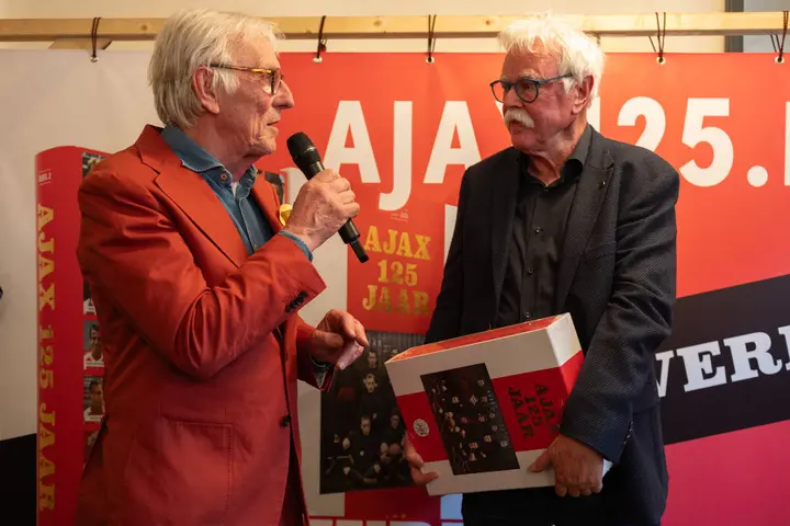 Matty Verkamman (r) wordt geëerd door Freek de Jonge. 'Ajax 125 jaar' is het laatste boek dat Verkamman uitgeeft.